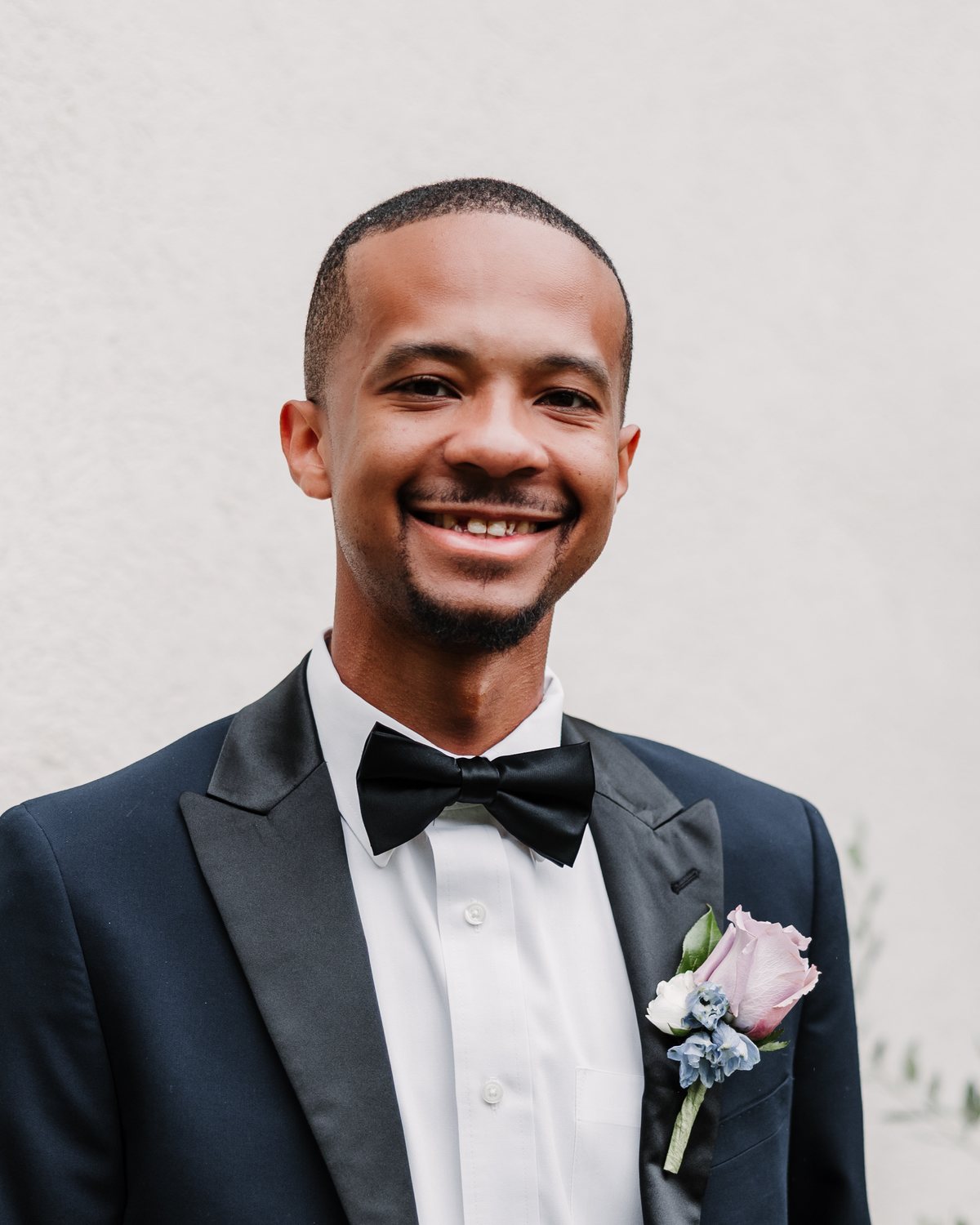 Jaylan Scott smiling at the camera in a navy tuxedo